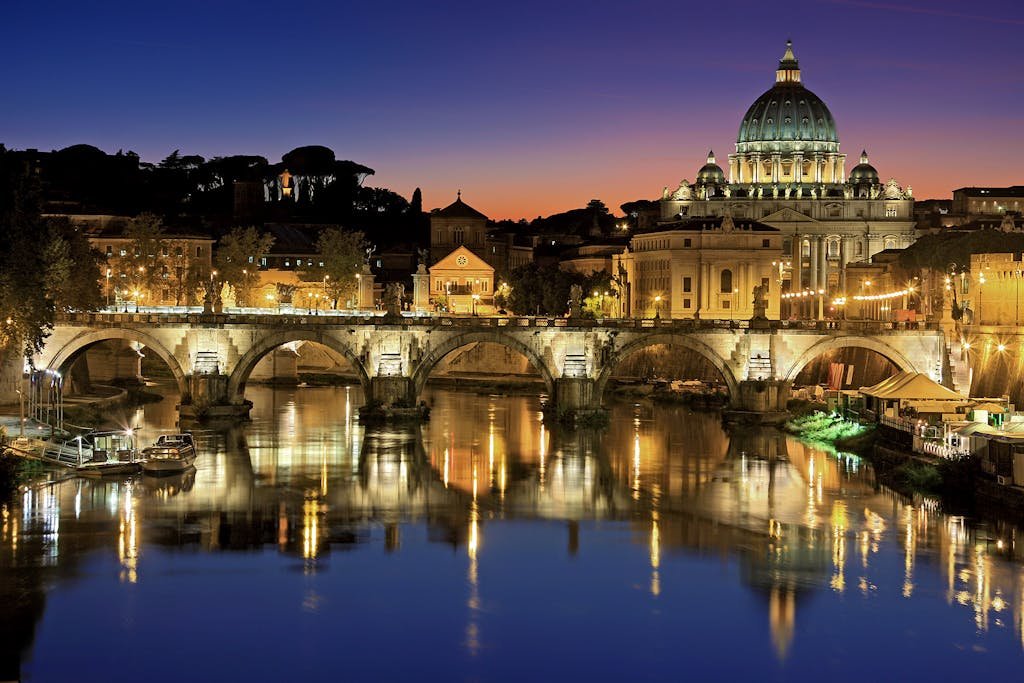 vegans taking in the Beautiful view of Saint Peter's Basilica and St. Angelo Bridge in Rome at sunset reflecting in the Tiber River.