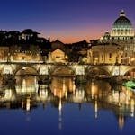 3 Day Rome Itinerary with Amazing Vegan Restaurant Options | The Ultimate Guide vegans taking in the Beautiful view of Saint Peter's Basilica and St. Angelo Bridge in Rome at sunset reflecting in the Tiber River.