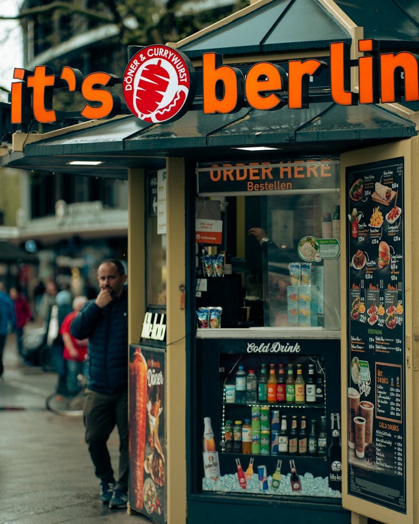 Berlin vegan street food stall selling currywurst, a popular German delicacy. Urban vibe with people nearby.
