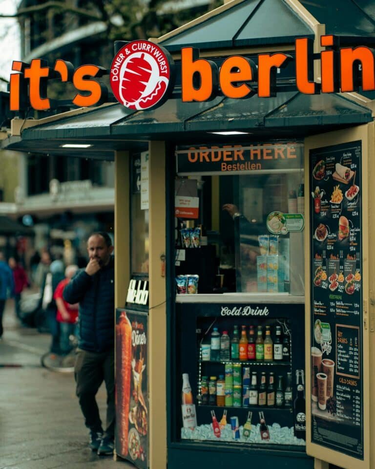 Berlin vegan street food stall selling currywurst, a popular German delicacy. Urban vibe with people nearby.