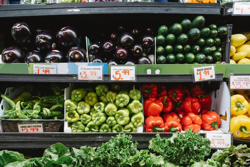 Colorful assortment of vegetables on display in a vegan supermarket, featuring peppers, eggplants, and squash.