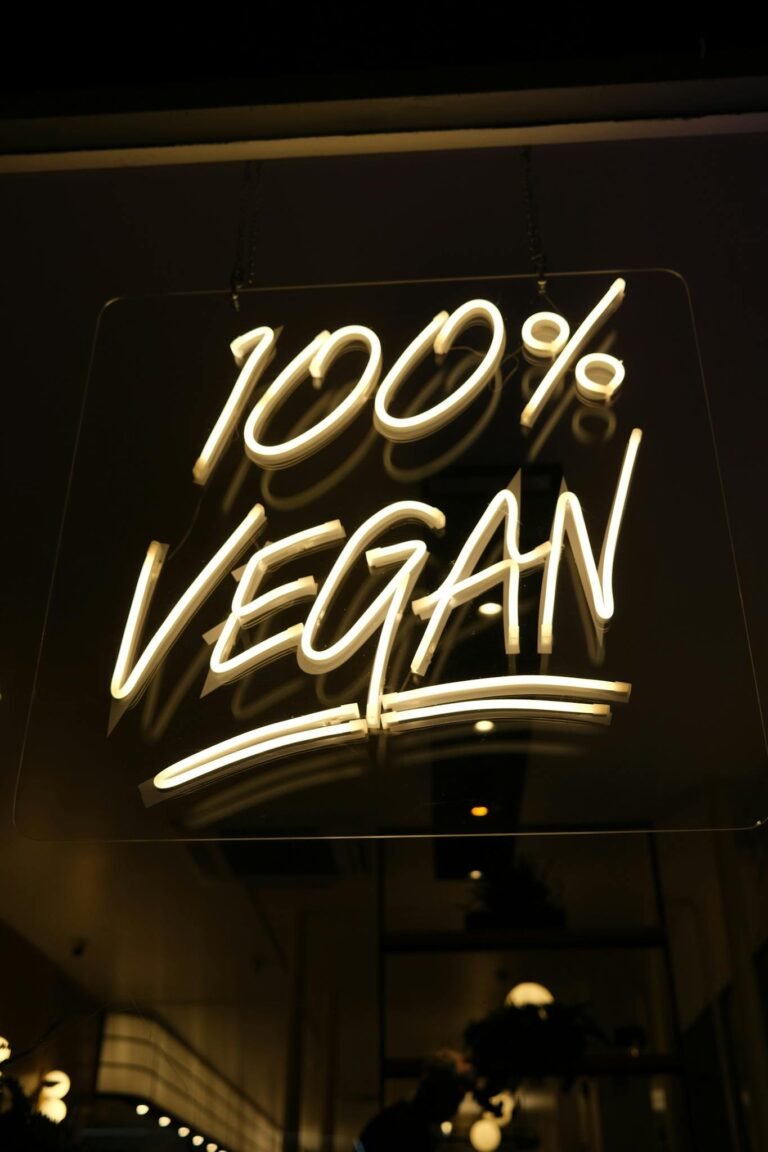 Glowing '100% Vegan' neon sign at a chic vegan restaurant, reflecting commitment to healthy eating.