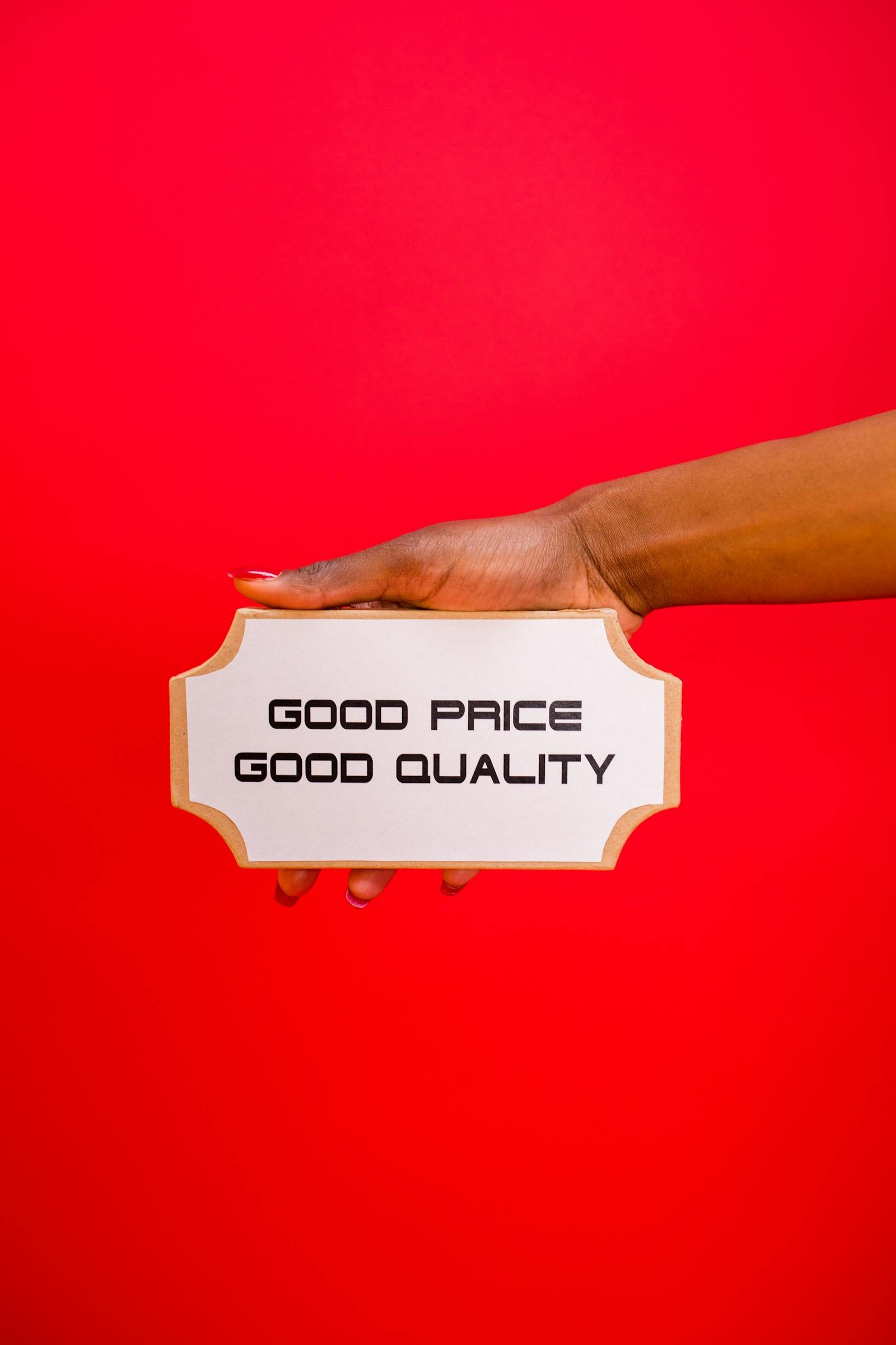 Services & Pricing A hand holding a sign with 'Good Price, Good Quality' text against a bright red background.