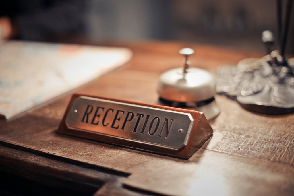 Close-up of a vegan friendly hotels reception desk showcasing a service bell and signage, emphasizing hospitality.