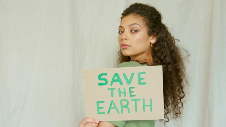 Portrait of a woman holding a 'Save the Earth' sign, promoting environmental awareness.