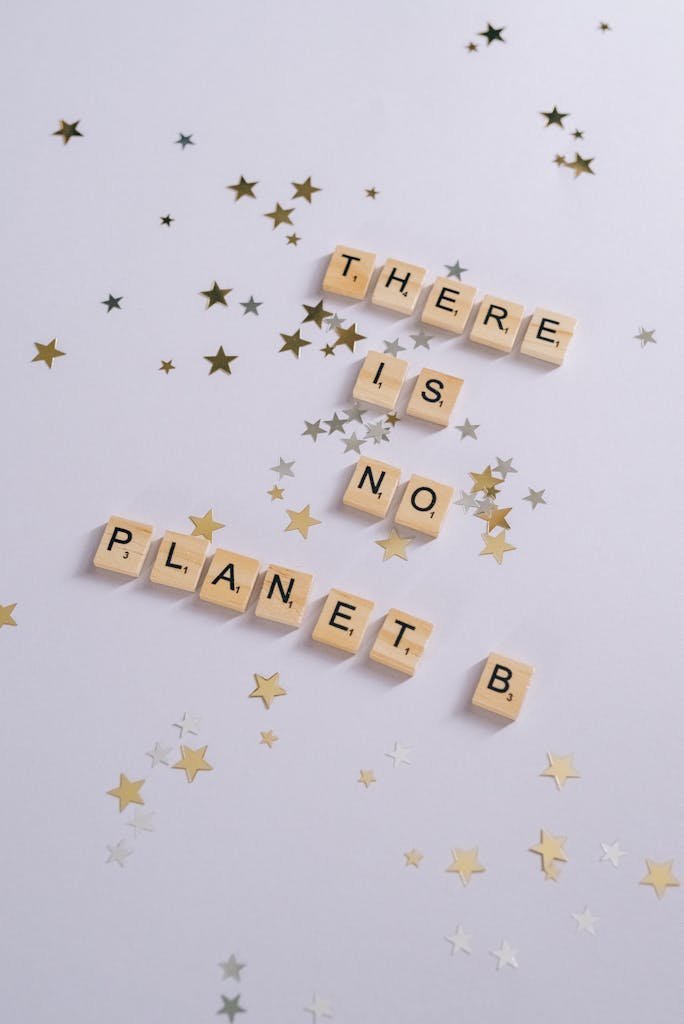 Scrabble tiles on a white background spell 'There is No Planet B' surrounded by star confetti. eco conscious travel