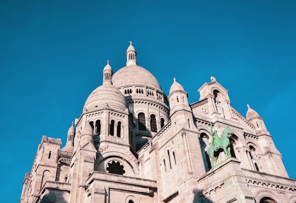 View of the Sacré-Cœur Basilica's architectural grandeur in Paris with a vibrant blue sky.