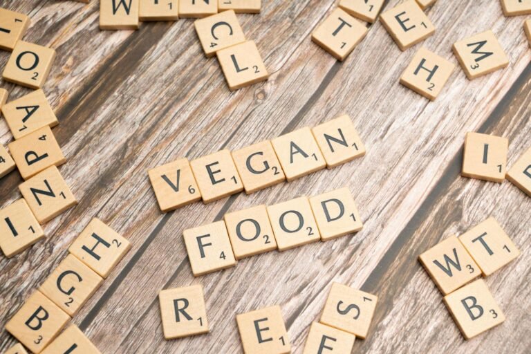 Wooden letter tiles spelling 'vegan airport food' creatively placed on a wooden surface, highlighting plant-based diet.