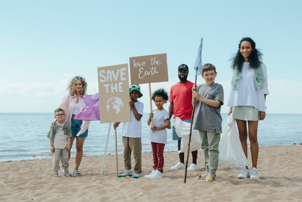 A diverse group of people on the beach holding signs advocating for saving the Earth.