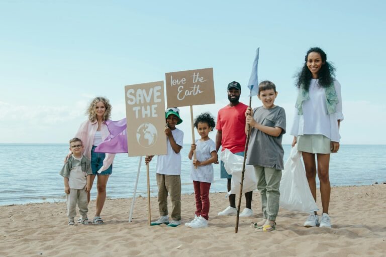 A diverse group of people on the beach holding signs advocating for saving the Earth.