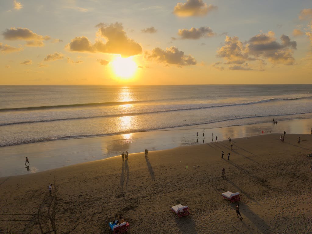 Beautiful sunset on Seminyak Beach, Bali with people enjoying the view and golden sands.