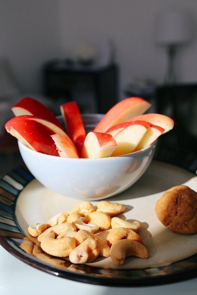 Bowl of sliced apples with cashews and fig on a plate. Perfect for healthy eating themes.