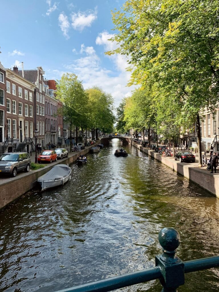 Charming view of a canal in Amsterdam with boats and classic architecture under a sunny sky.