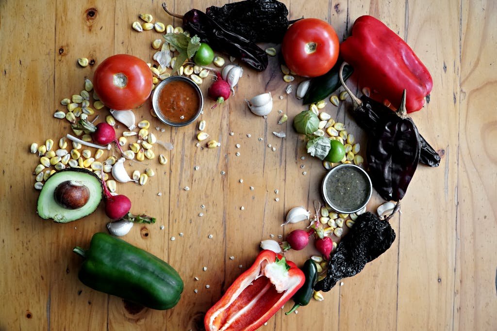 Colorful Mexican ingredients on wooden background, highlighting peppers, radishes, avocado, and sauces.