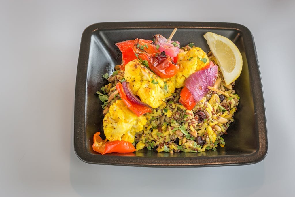 Delicious grilled vegetable skewer over mixed rice, garnished with a lemon wedge.