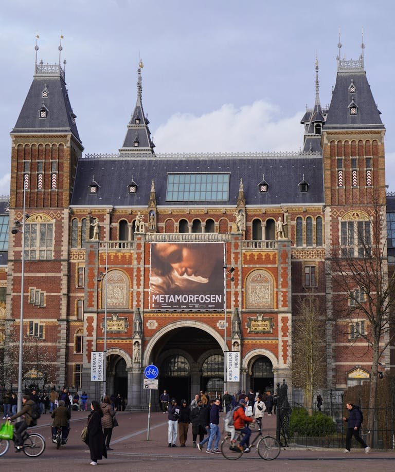 Front view of the Rijksmuseum in Amsterdam featuring the Metamorfosen exhibition banner.