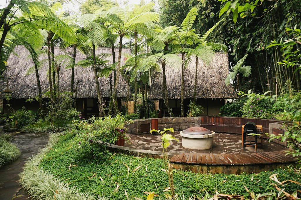 Serene tropical garden featuring a traditional thatched roof hut surrounded by lush greenery.