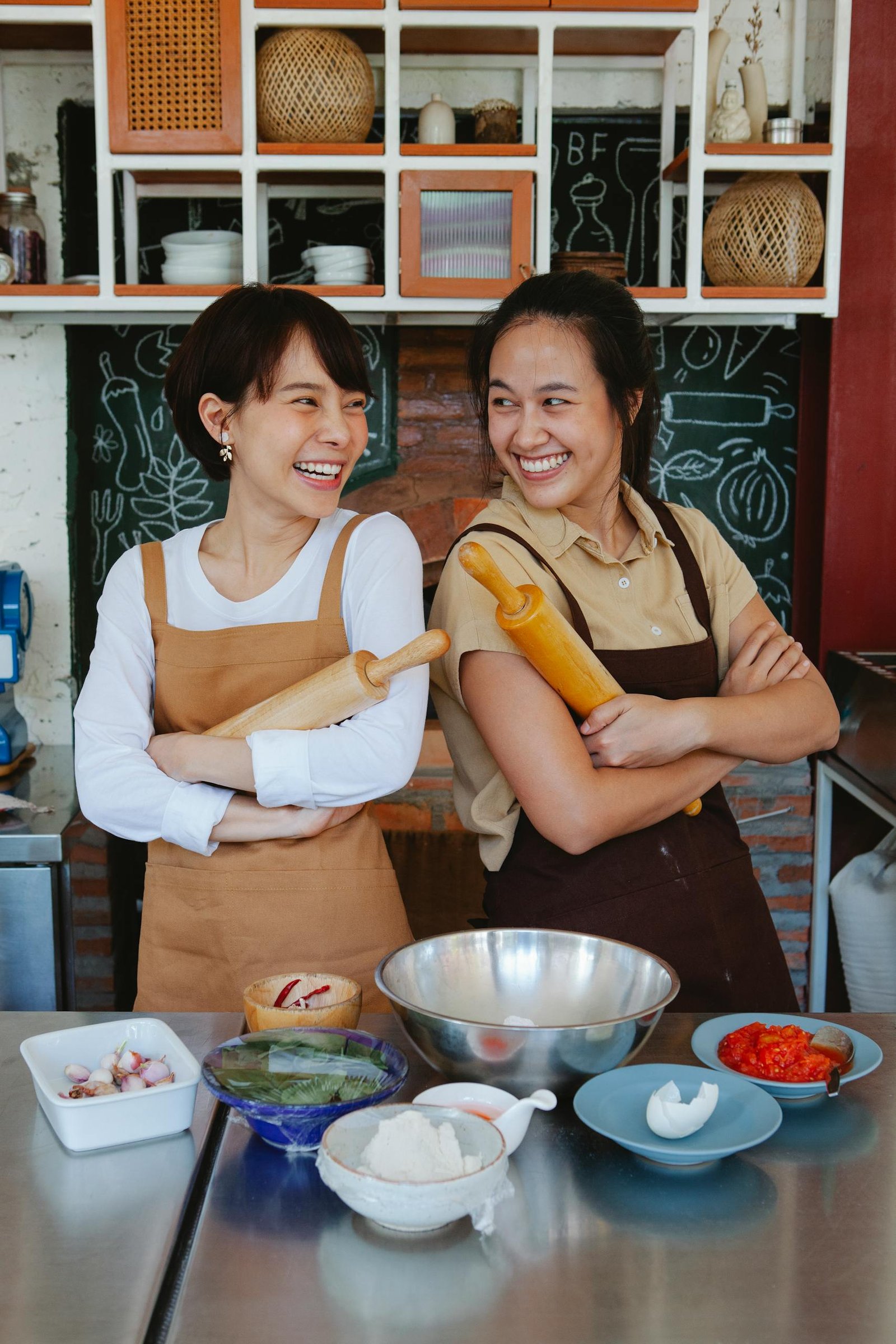 Two women smiling while preparing ingredients in a cozy kitchen setting.