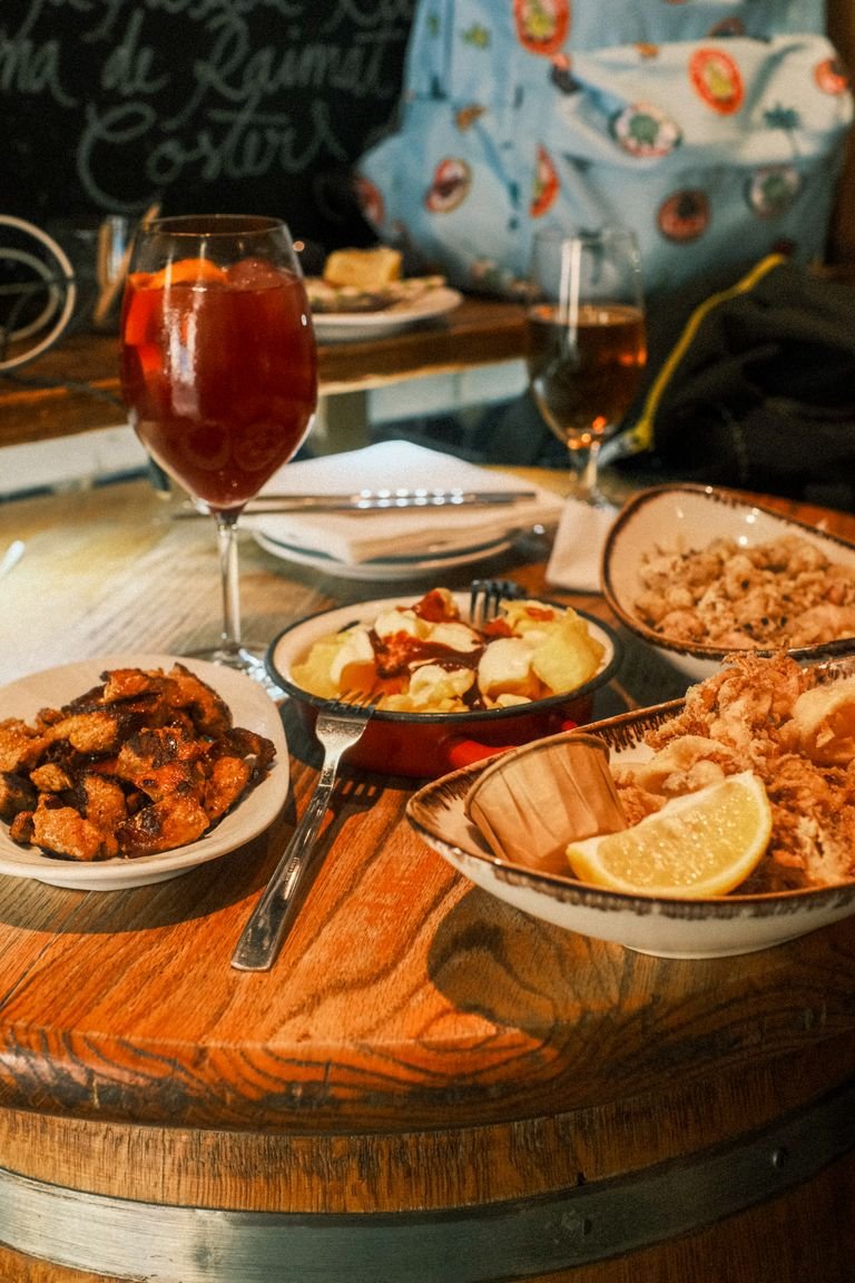 vegan food tours. A table set with a variety of Spanish tapas and a glass of sangria in a cozy Barcelona restaurant.
