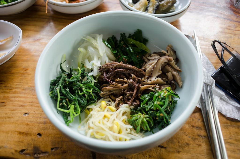 A vibrant Korean vegetable dish featuring an array of fresh greens and mushrooms.