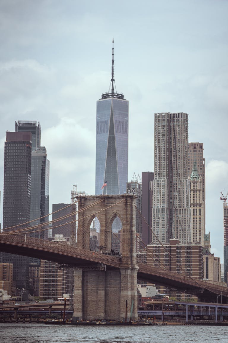 Brooklyn Bridge with Manhattan's skyline, showcasing iconic New York landmarks under cloudy skies.