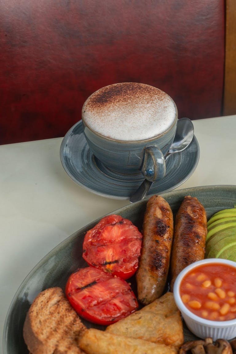 Delicious classic English breakfast featuring sausages, beans, and coffee.