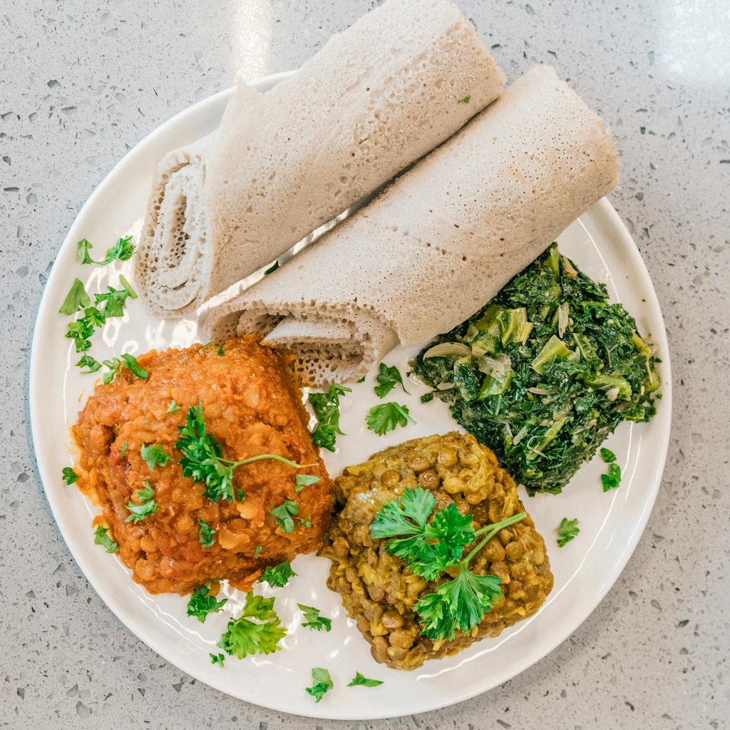 Delicious Ethiopian dish featuring injera and vibrant vegetable stews on a white plate.