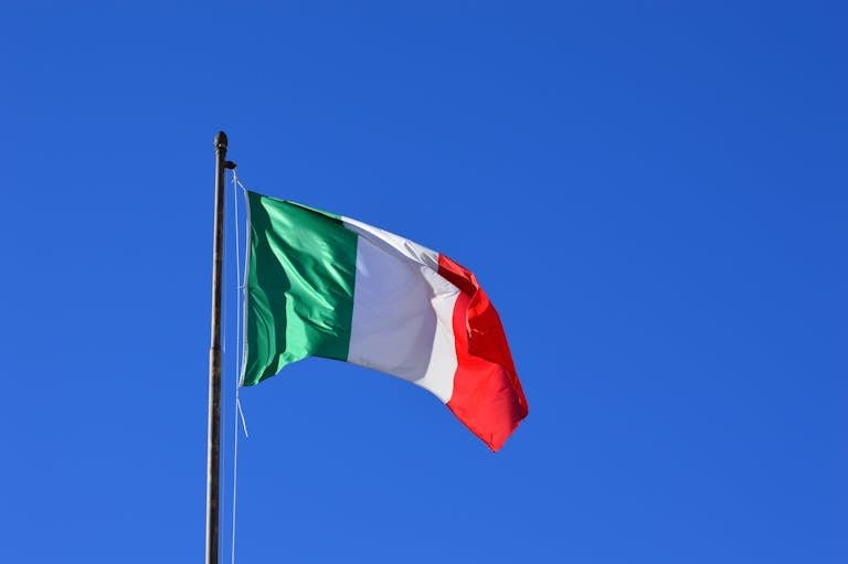 Italian flag flying against a vibrant blue sky, symbolizing national pride and identity.