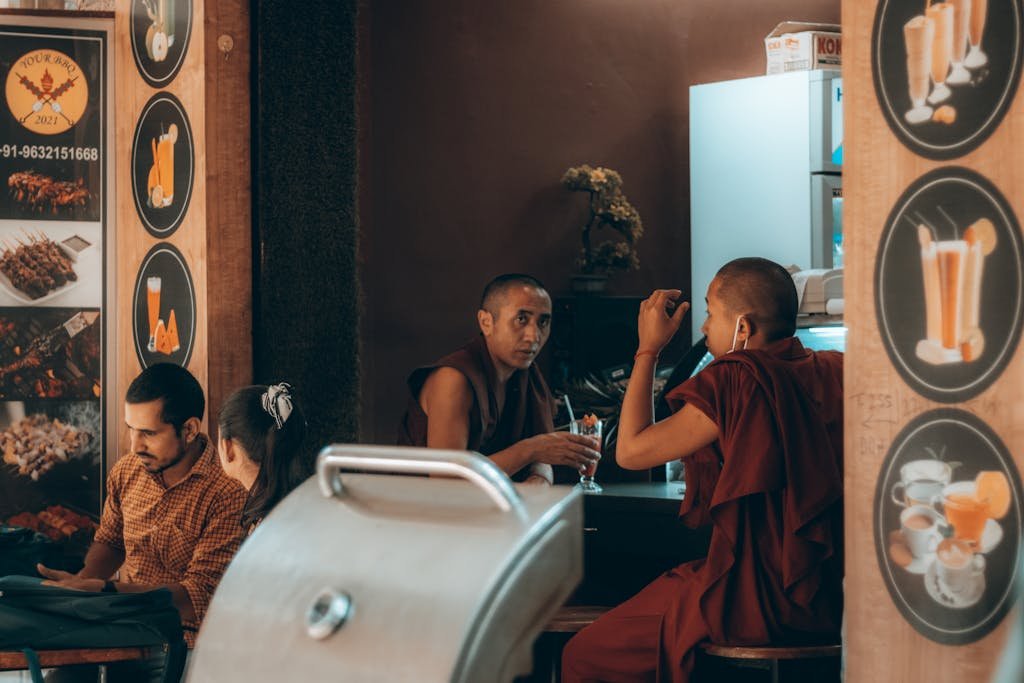 Monks in traditional robes having a discussion in a cozy restaurant environment.