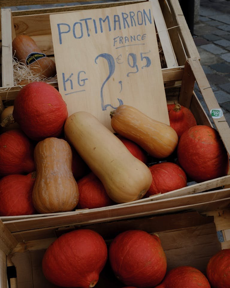 Rustic market scene with pumpkins and squash for sale in wooden crates with price signage.