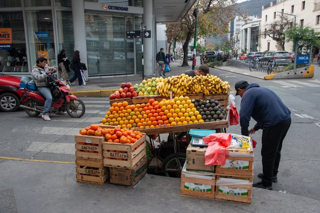 Vibrant fruit stand on a street corner in Salta, Argentina, featuring fresh bananas, oranges, and avocados.