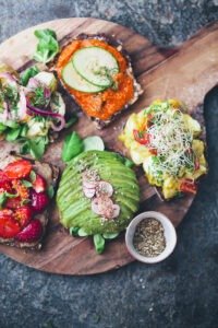 Vegan smørrebrød open-faced rye bread sandwich with vegetables and toppings on a wooden board" 