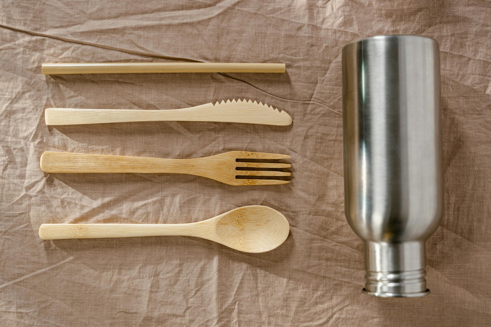 A set of bamboo cutlery alongside a stainless steel bottle, reflecting a zero waste lifestyle.