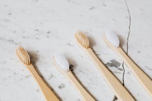 Four bamboo toothbrushes arranged on a cracked marble surface, promoting eco-friendly dental care.