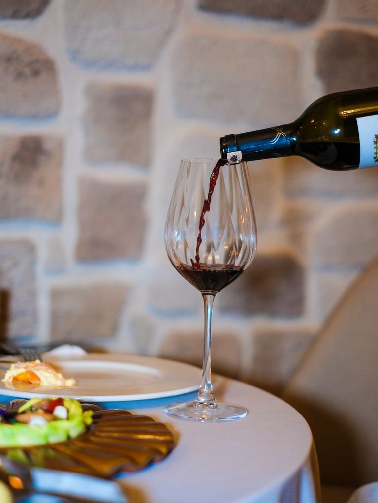 Elegant scene of red wine being poured in a cozy vegan restaurant ambiance.