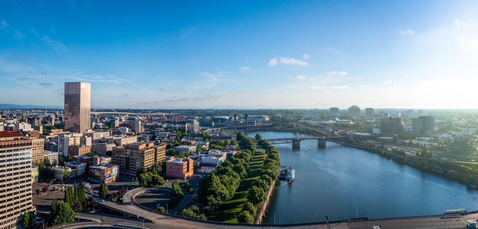 A stunning aerial view of Portland skyline with rivers and bridges under a clear blue sky.