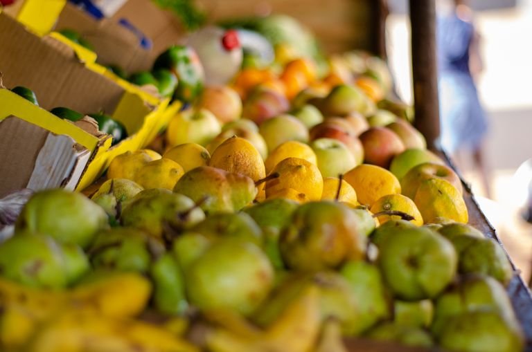 A vibrant display of fresh fruits at a local market stall with pears, apples, and lemons arranged.