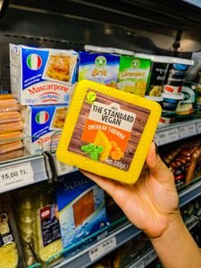 Close-up of vegan cheddar cheese block in a grocery store aisle.