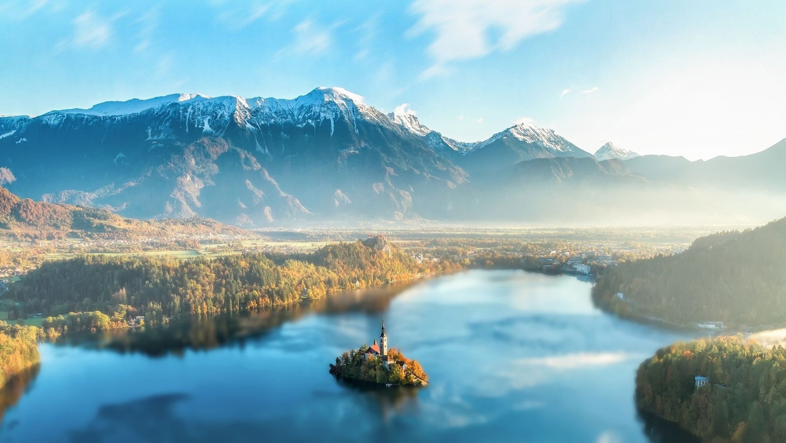 Majestic Lake Bled with church on island, surrounded by Julian Alps under sunset light.