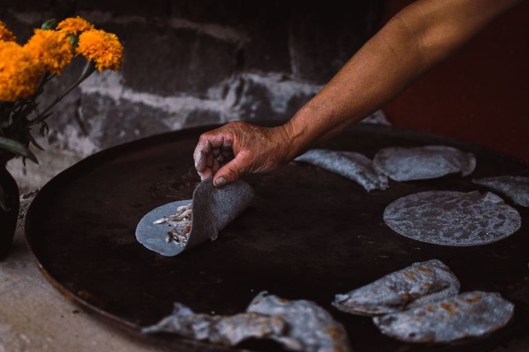 Mexico City street vendor making tlacoyos, a naturally vegan corn dish