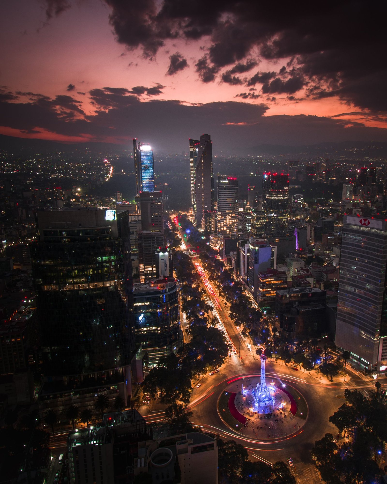 Stunning aerial view of Mexico City skyline during twilight with vibrant city lights and dramatic clouds.
