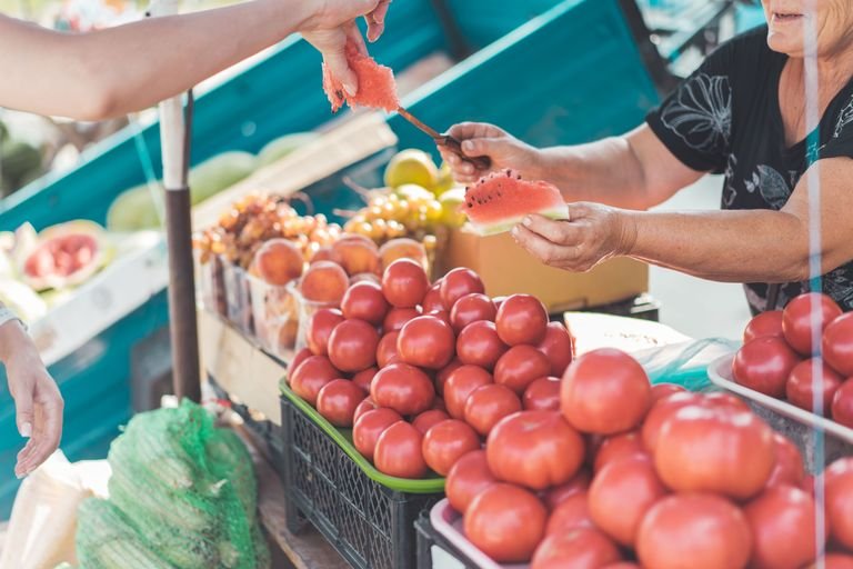 Vegan traveler asking a market vendor about produce
