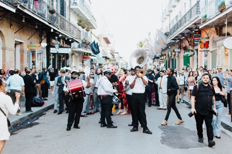 A lively street parade with musicians and crowds in the heart of New Orleans, capturing the festive spirit of the city.
