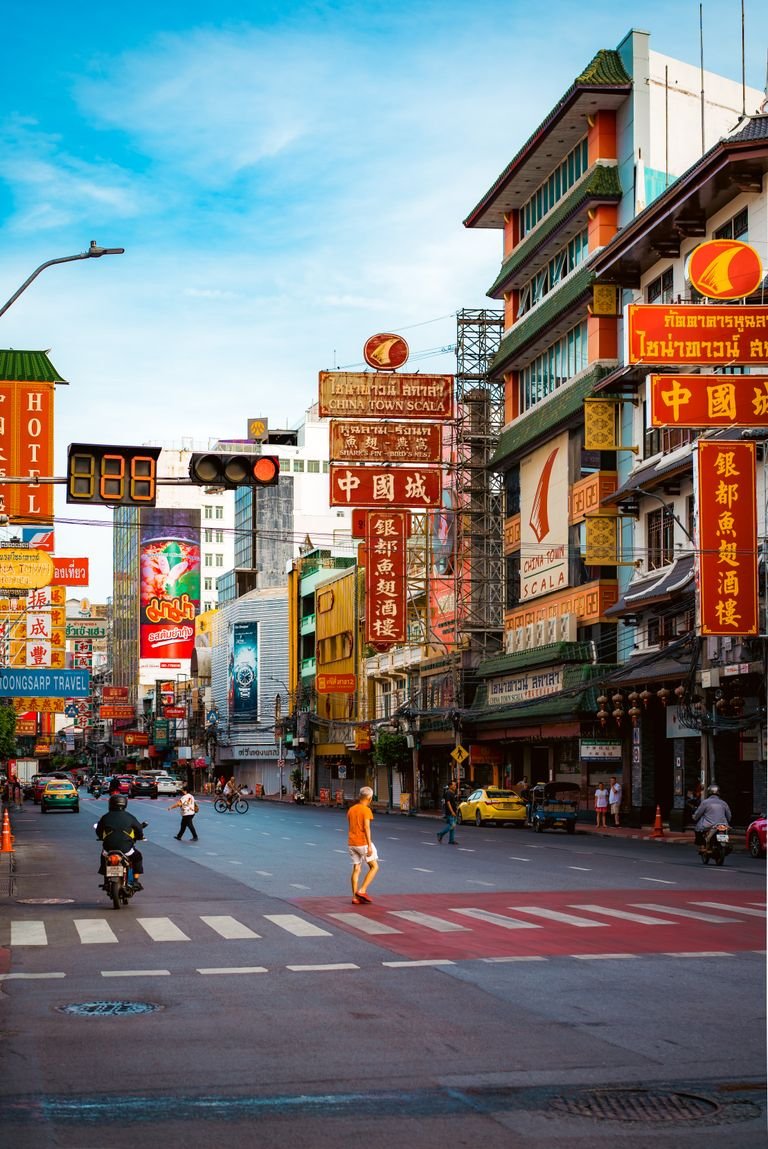 A lively street scene from Chinatown, Bangkok showcasing cultural signs and urban life.