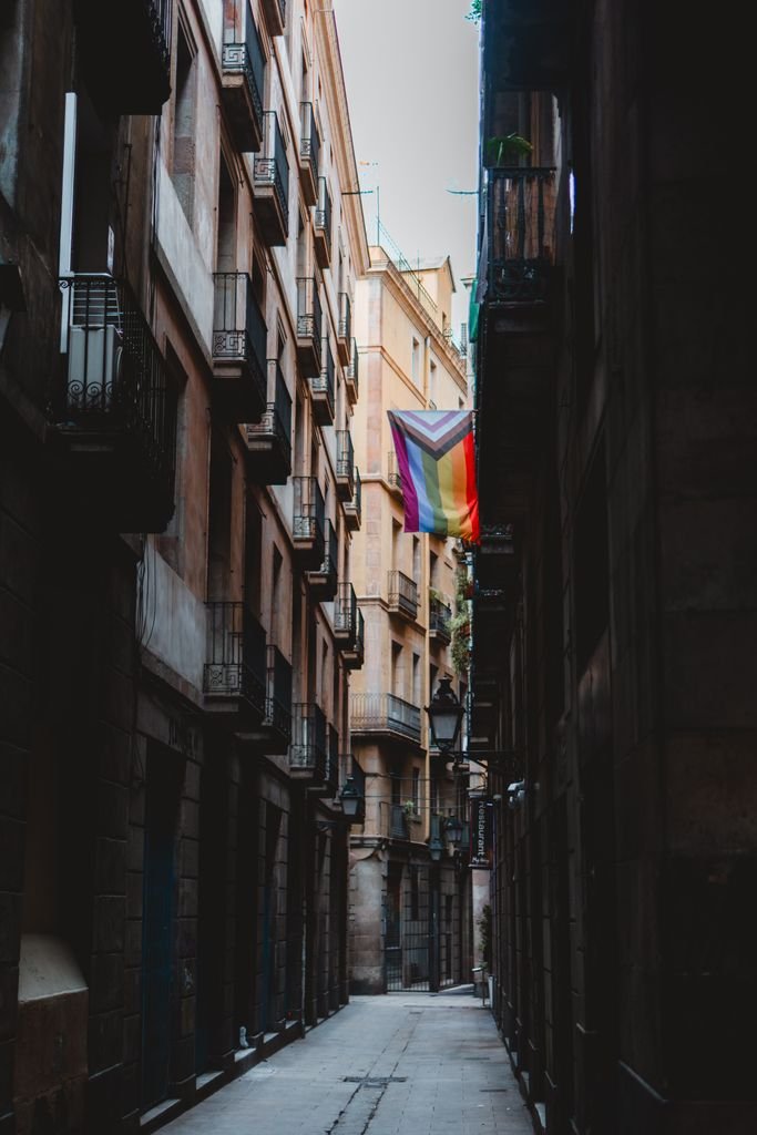 A vibrant flag hangs in the narrow streets of Barcelona, capturing the essence of the city's urban charm.
