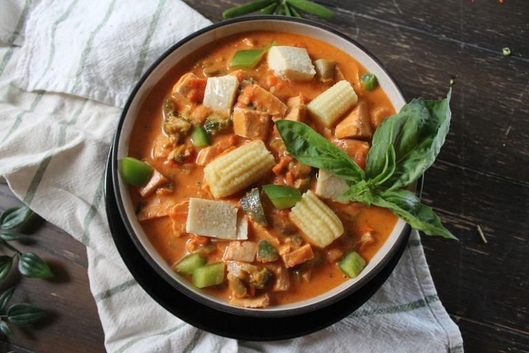 Appetizing vegan Thai red curry dish with tofu and fresh vegetables in a bowl.