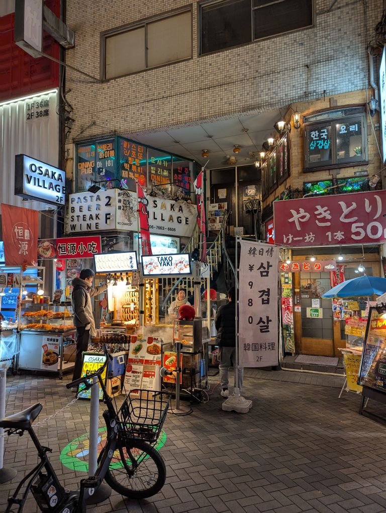 Bustling night scene in Osaka's shopping area, featuring lively restaurants and shops.