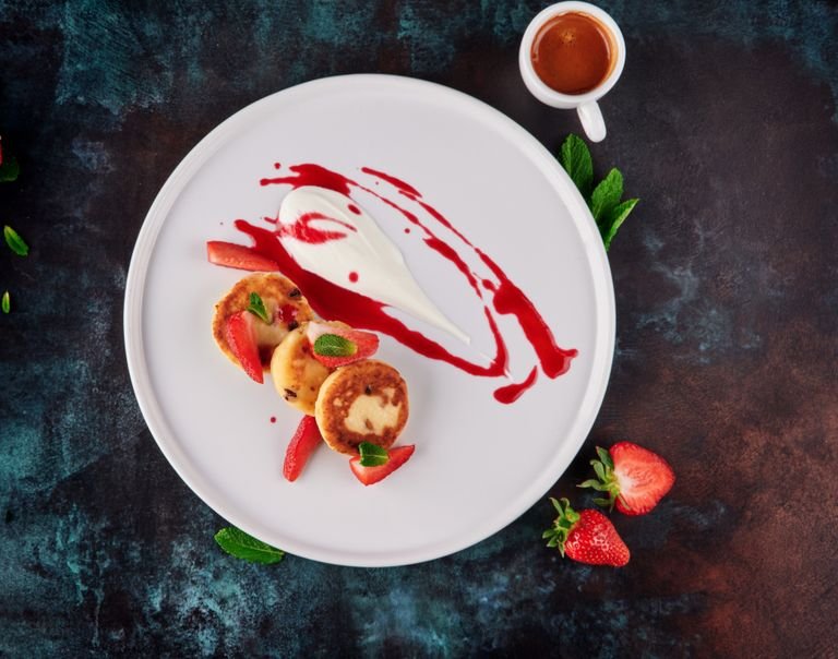 Elegant gourmet presentation of strawberry cheesecake with sauce and mint leaves, ideal for culinary showcases.