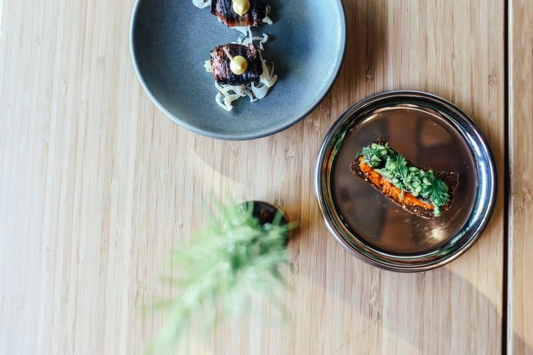 Elegant plating of gourmet dishes on wooden table, showcasing fine dining artistry.