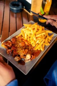 Plate of vegan currywurst with sauce and crispy french fries, a classic fast food meal.